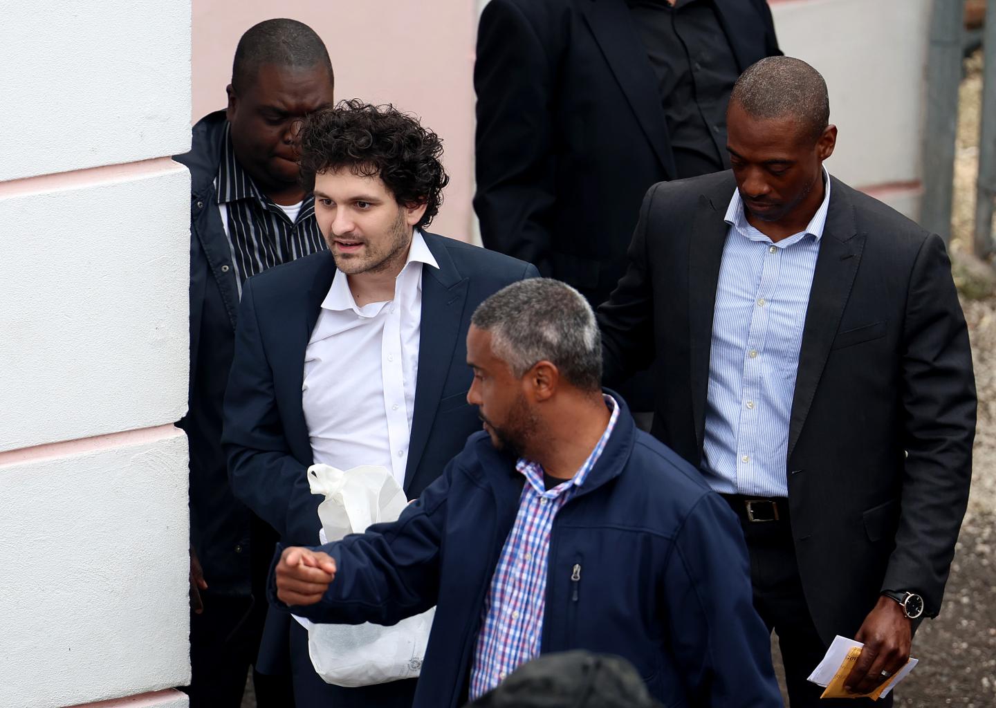 Sam Bankman-Fried surrounded by authorities in the Bahamas.