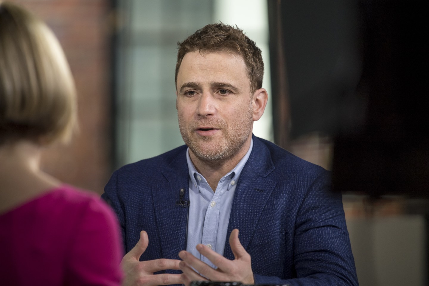 Slack CEO Stewart Butterfield with his hands postured as he speaks to a woman