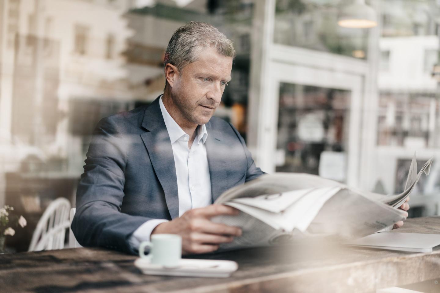 Businessman in a cafe reads stories in a newspaper
