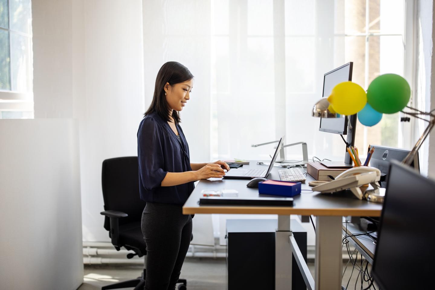 Woman working at ergonomic standing desk having a teleconference.