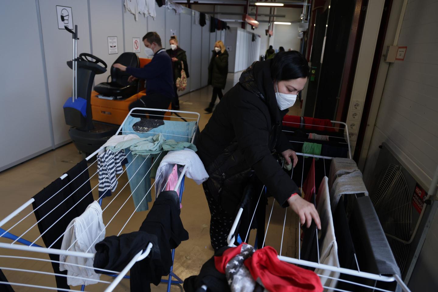 A woman from the war-scarred Ukrainian region of Zaporizhzhia hangs laundry in a hall that is her temporary hom