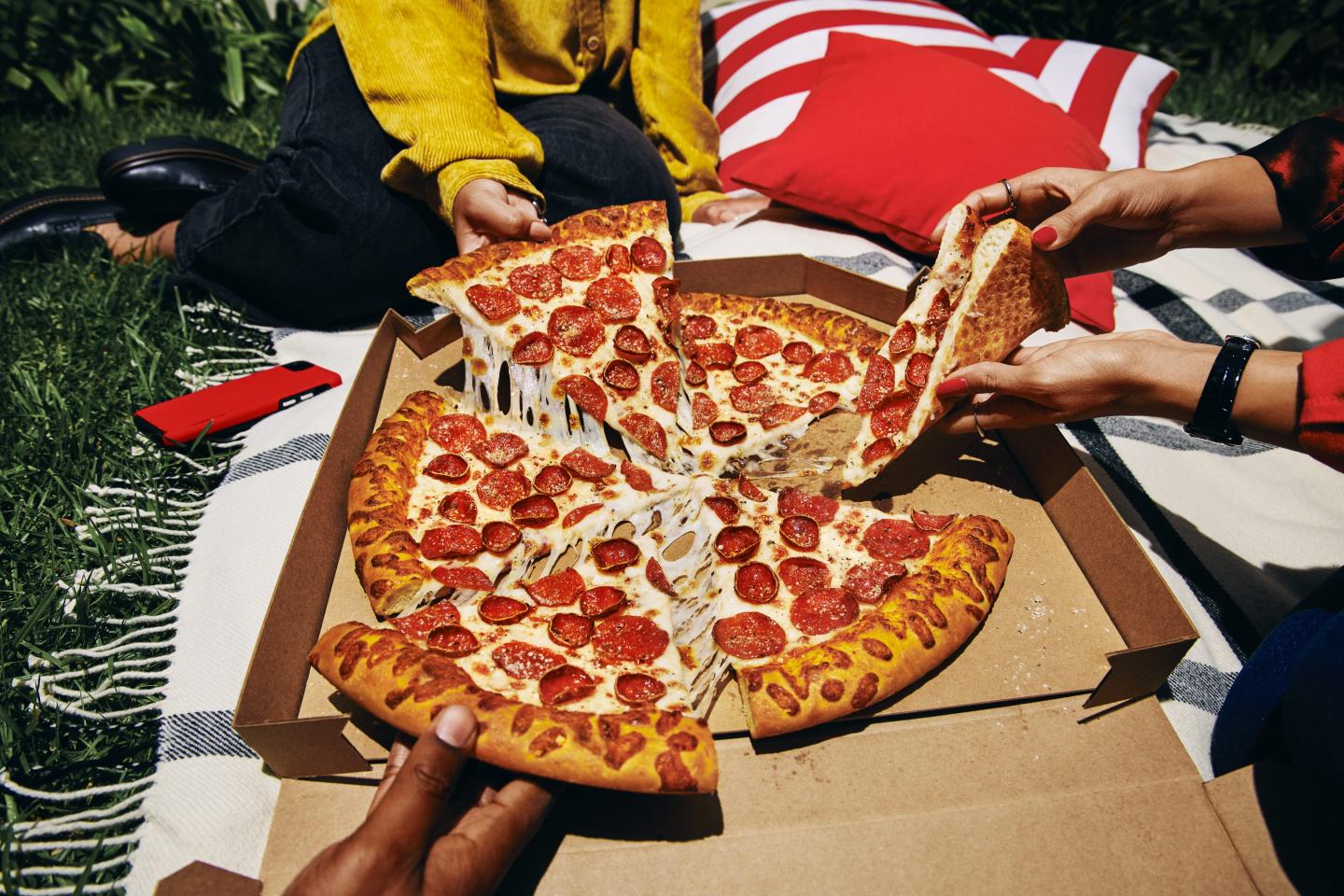 People grabbing slices of pizza