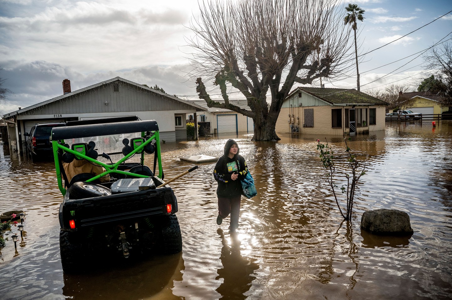 A woman wades through floodwaters in California.
