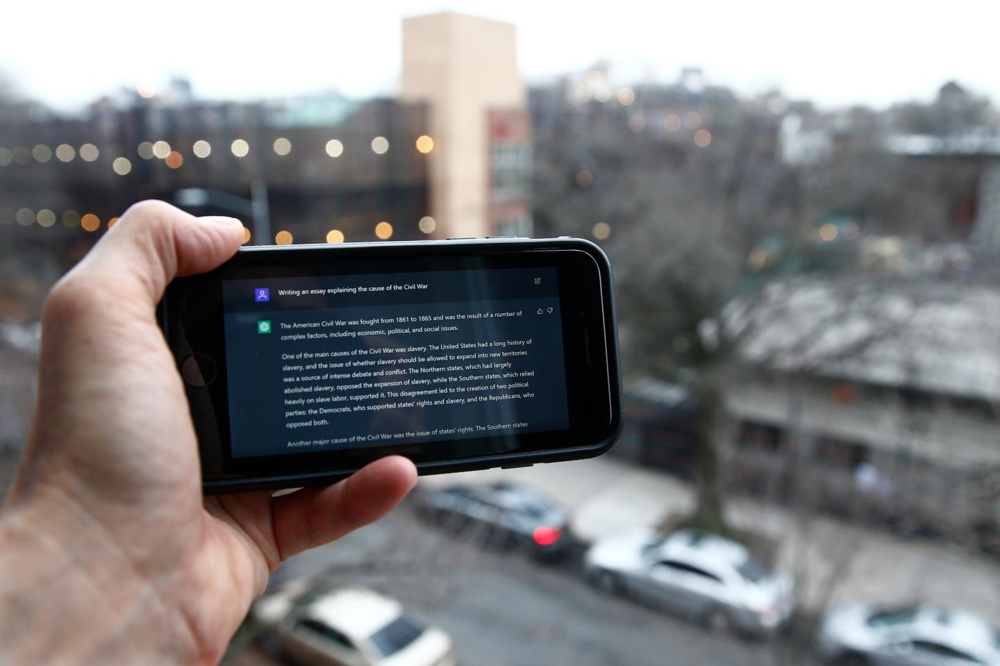 Someone holding a smart phone with a ChatGPT prompt.