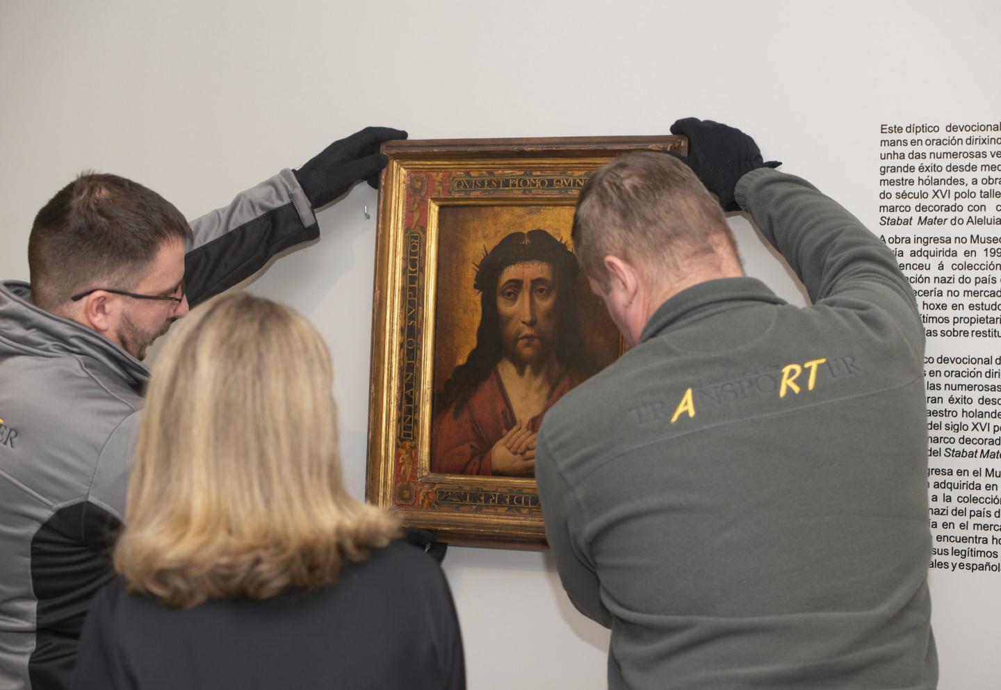 People take down a painting of Jesus Christ.