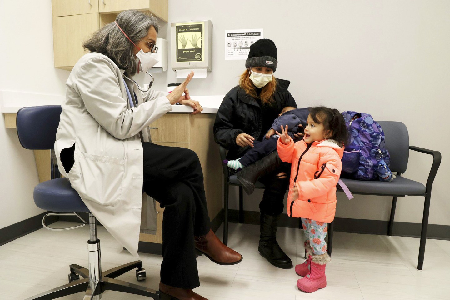 Dr. Pilar Guerrero, an emergency room doctor at Stroger Hospital, playfully counts with Yansa Torres, as her mother, Darling, holds her son, Yahir, at the Cook County Health Clinic in Chicago on Nov. 18, 2022.