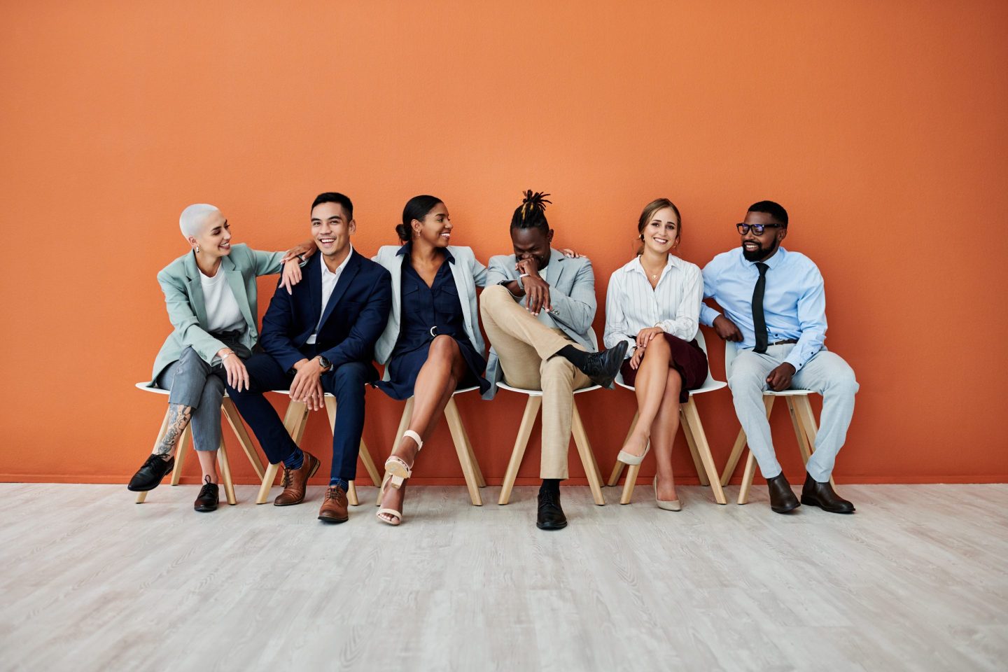 A group of businesspeople sitting against an orange background