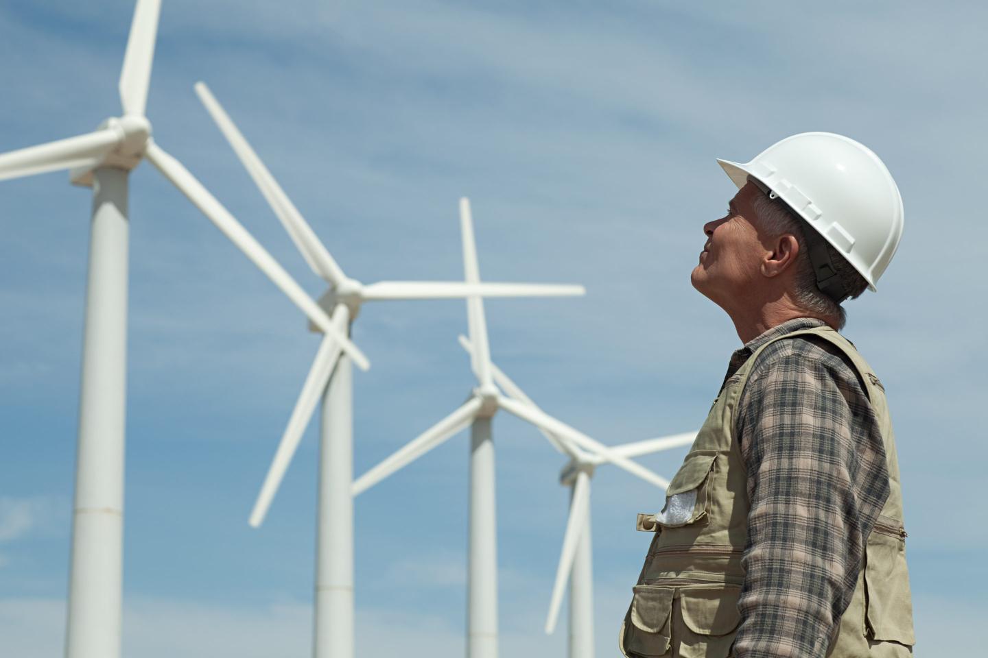 Man in hard hat looking at wind turbines