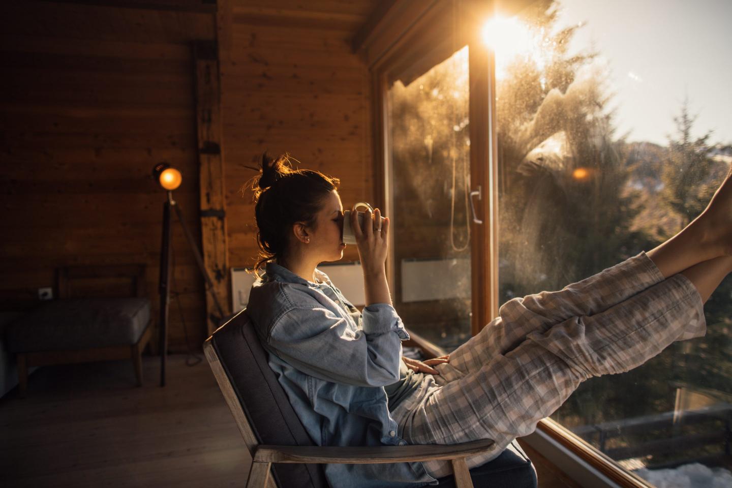 Woman drinks her morning coffee in a cost nordic cabin
