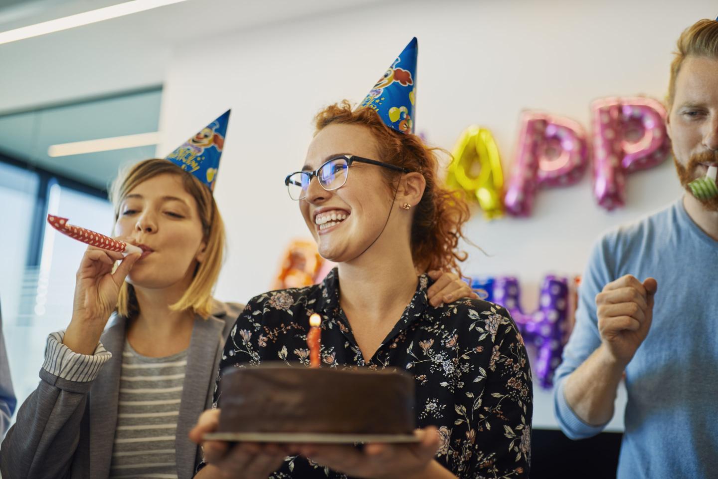 Colleagues having a birthday celebration in office with cake