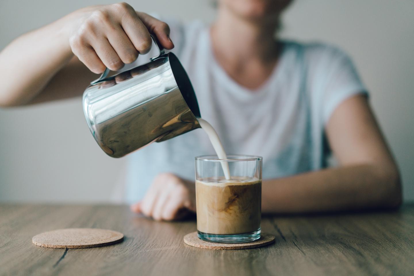 Iced coffee with milk being poured in.