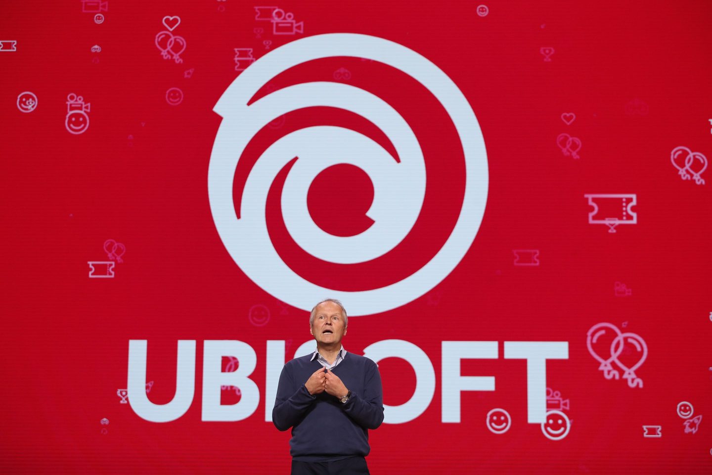 Ubisoft CEO Yves Guillemot in front of a red backdrop with the Ubisoft logo.