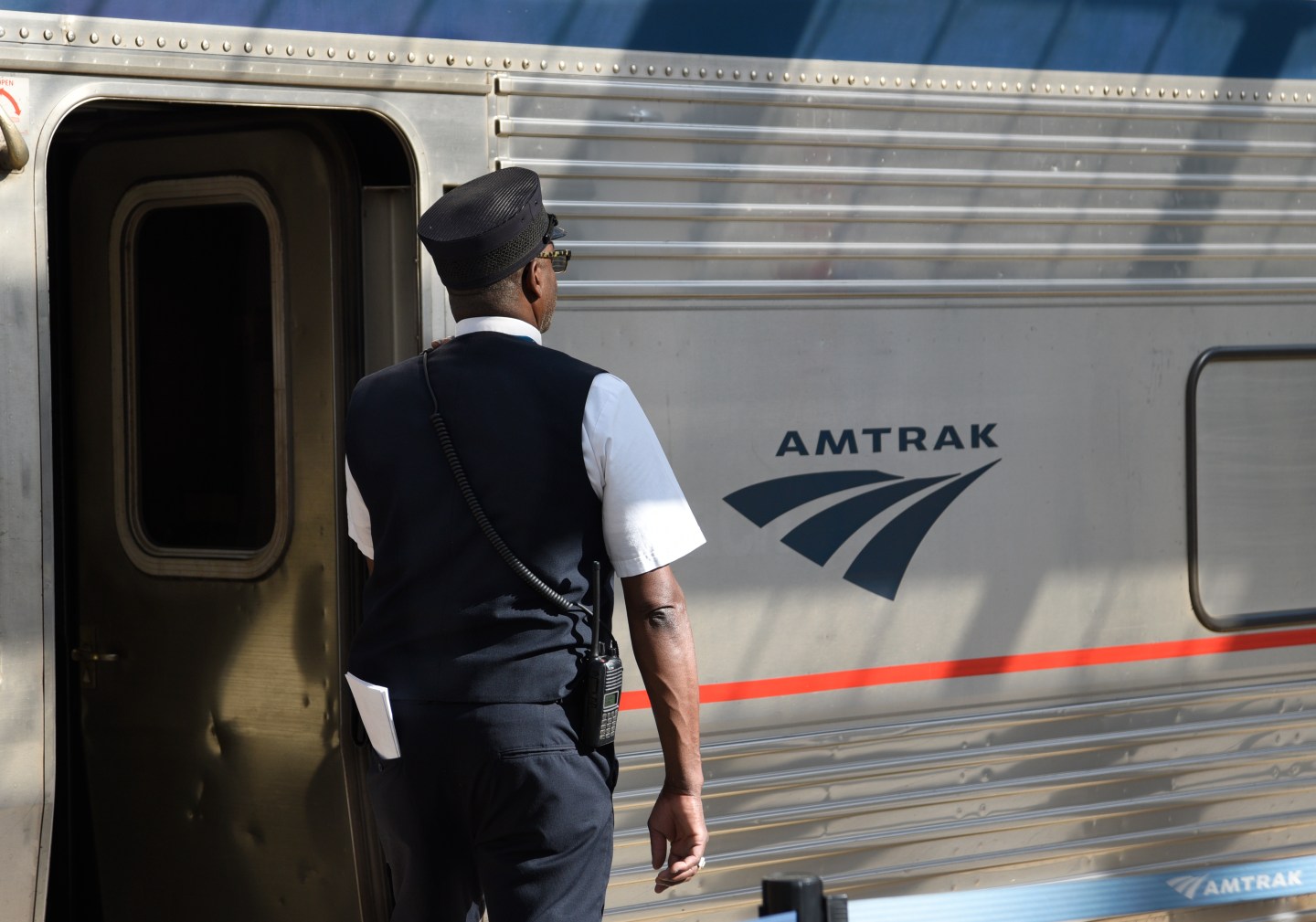 A conductor standing next to an Amtrak train.