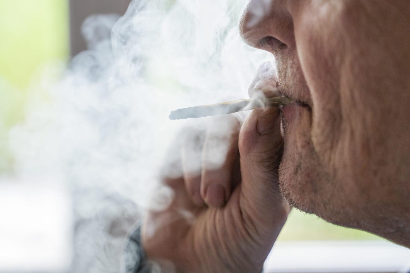 Senior man at home smoking marihuana joint