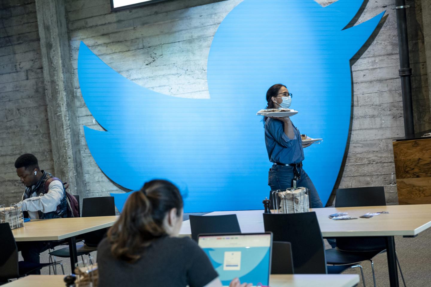 An employee carries plates of food at Twitter headquarters in San Francisco