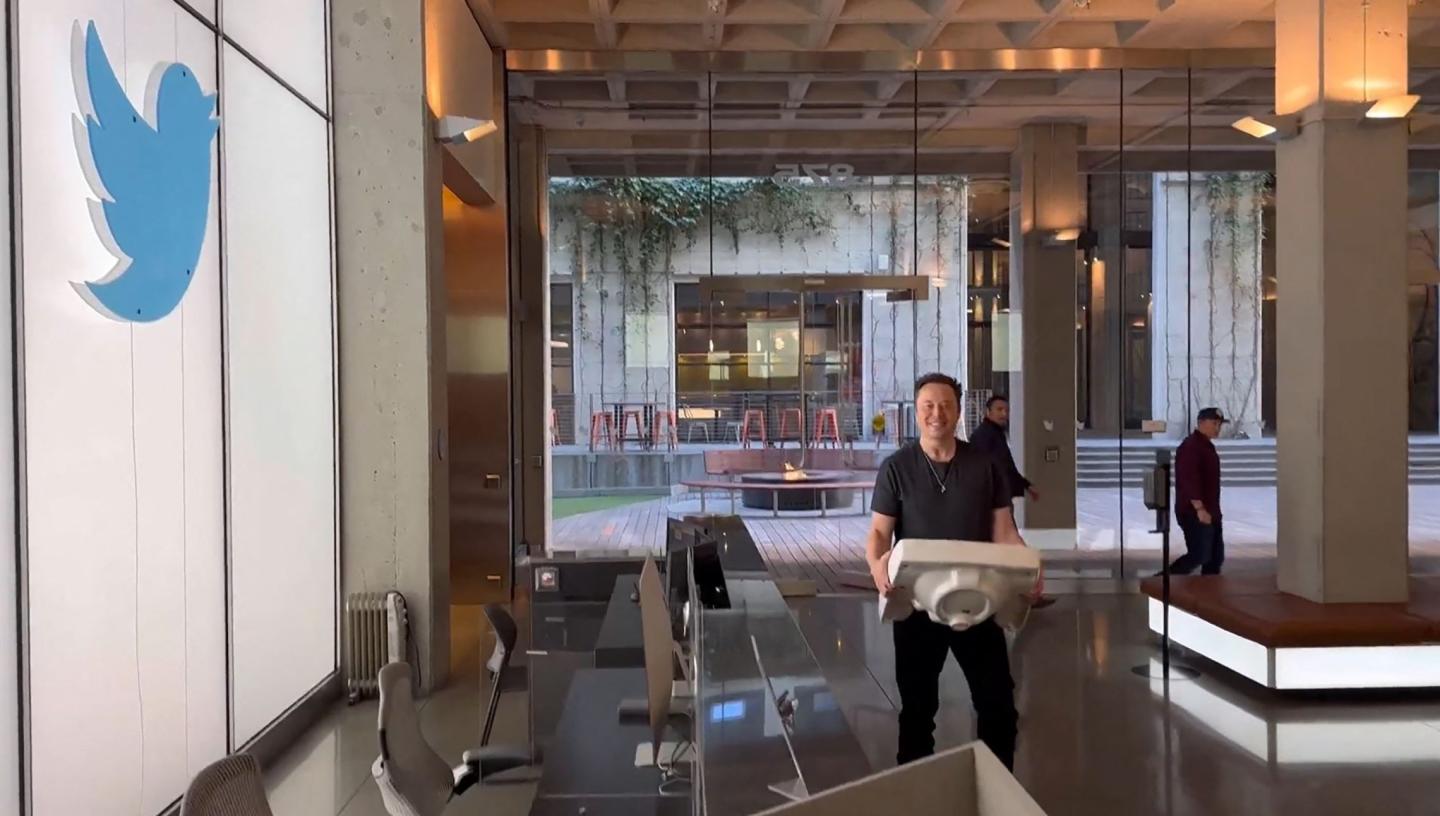 Elon Musk at Twitter carrying a desktop