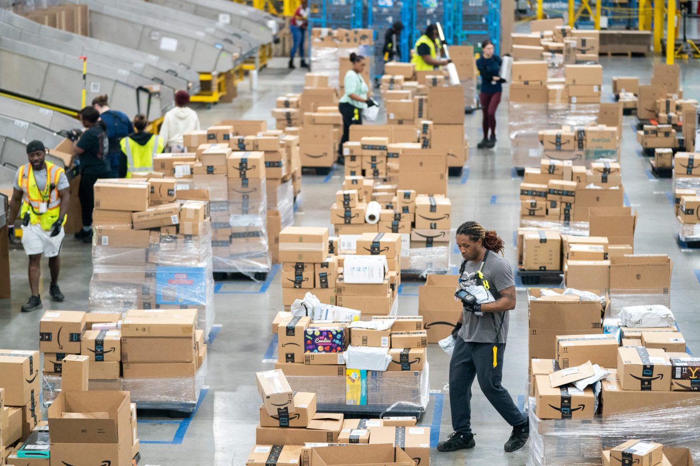 Workers sort packages by zip code during a media tour of the Amazon AGS5 facility on October 27, 2022 in Appling, Georgia.