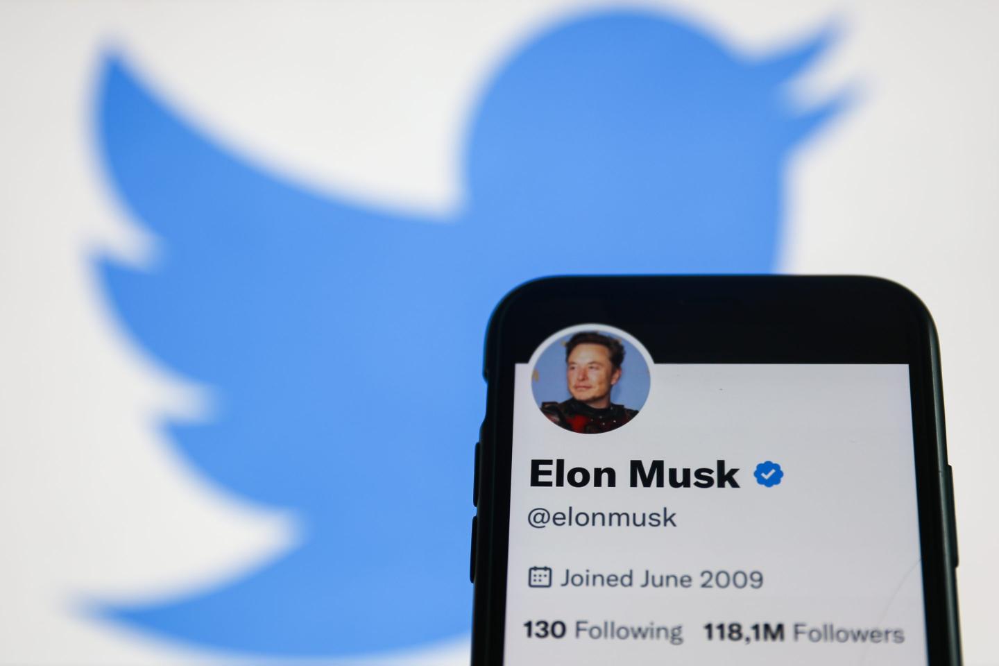 Elon Musk Twitter account displayed on a phone screen and Twitter logo