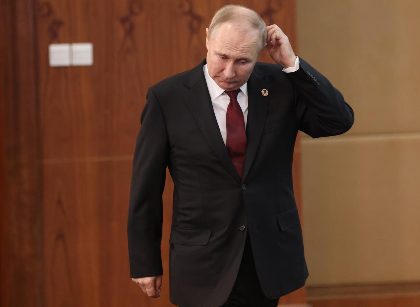 Vladimir Putin walking while scratching his head