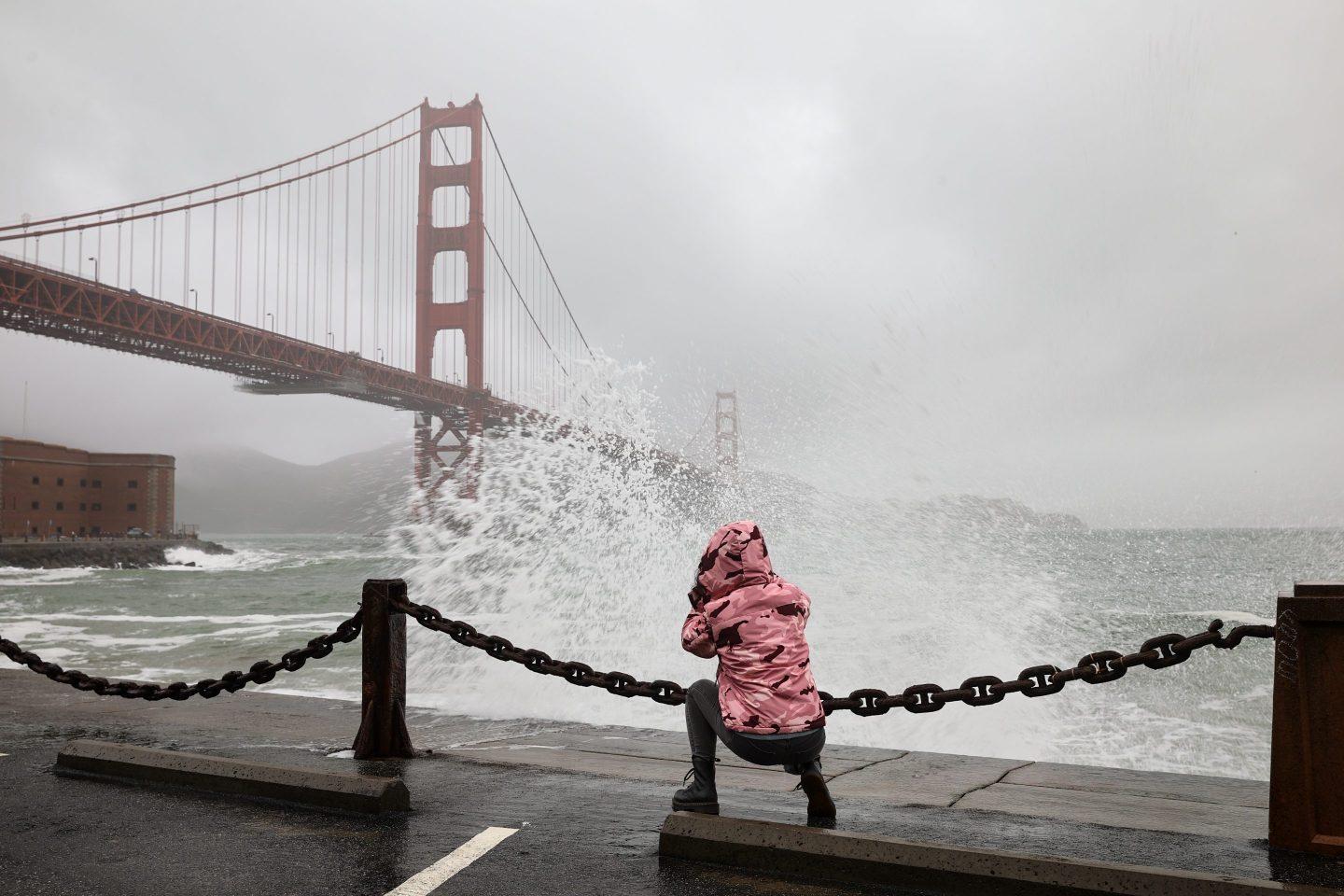 Photo of waves lapping over a walkway with the Golden Gate Bridge in the background.