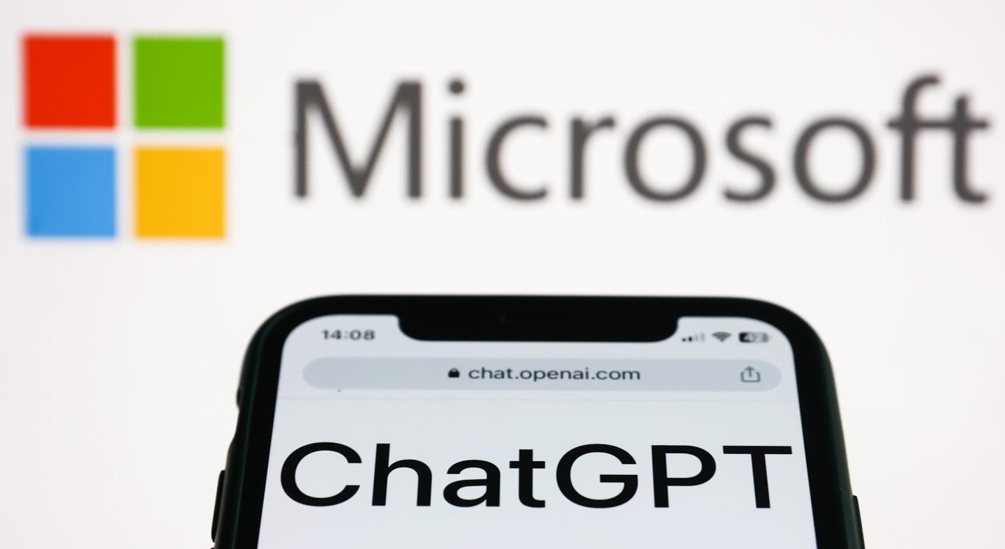 The Microsoft name and logo is pictured above a smartphone screen showing the word ChatGPT