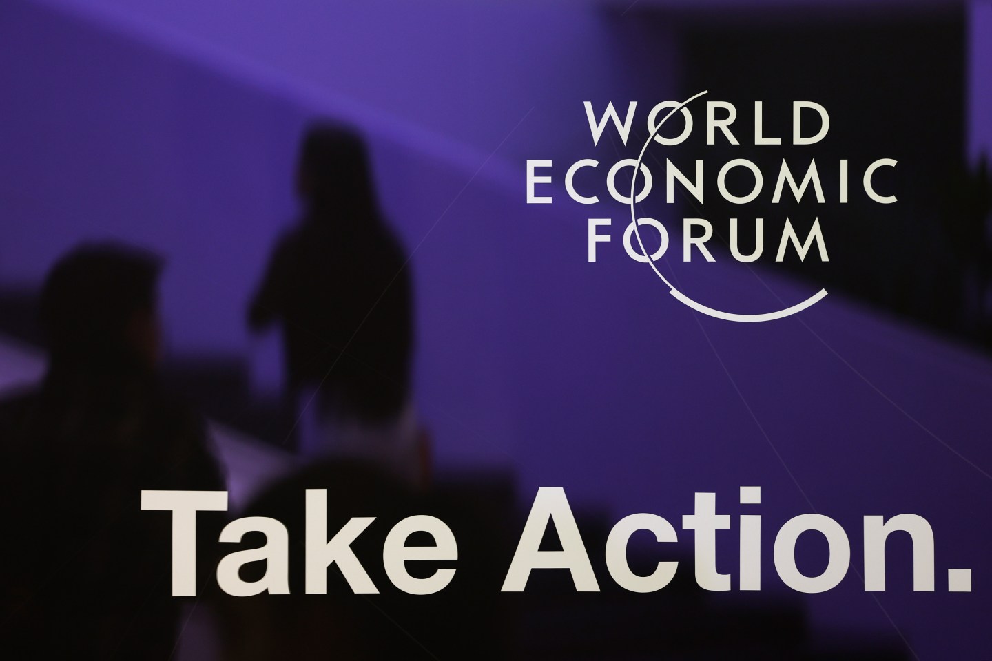 A logo and a sign reading 'Take Action' inside the Congress Center on day three of the World Economic Forum (WEF) in Davos, Switzerland, on Thursday, Jan. 19, 2023.