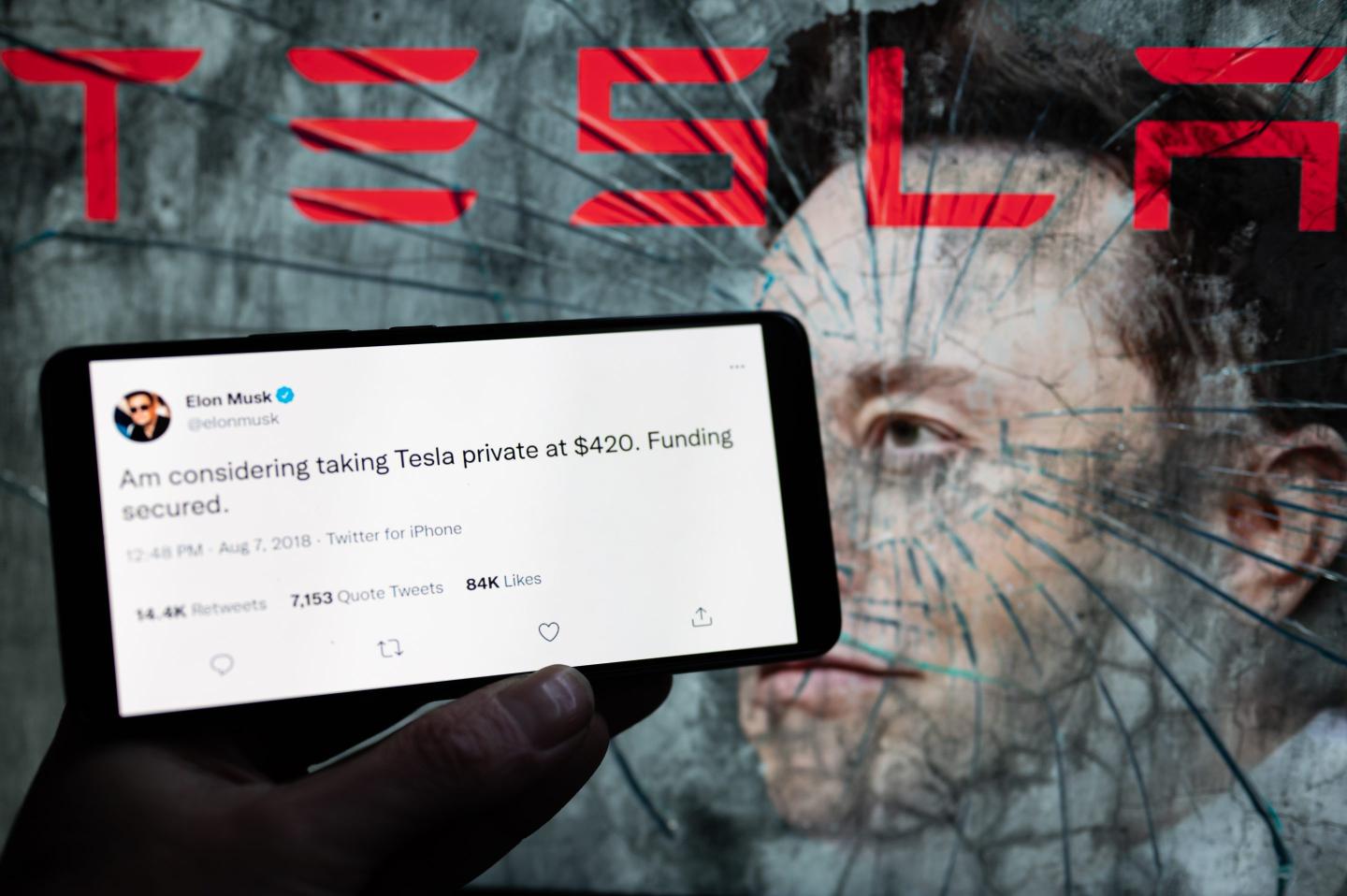 Elon Musk Tesla tweet displayed on mobile with in the background Elon musk on screen.