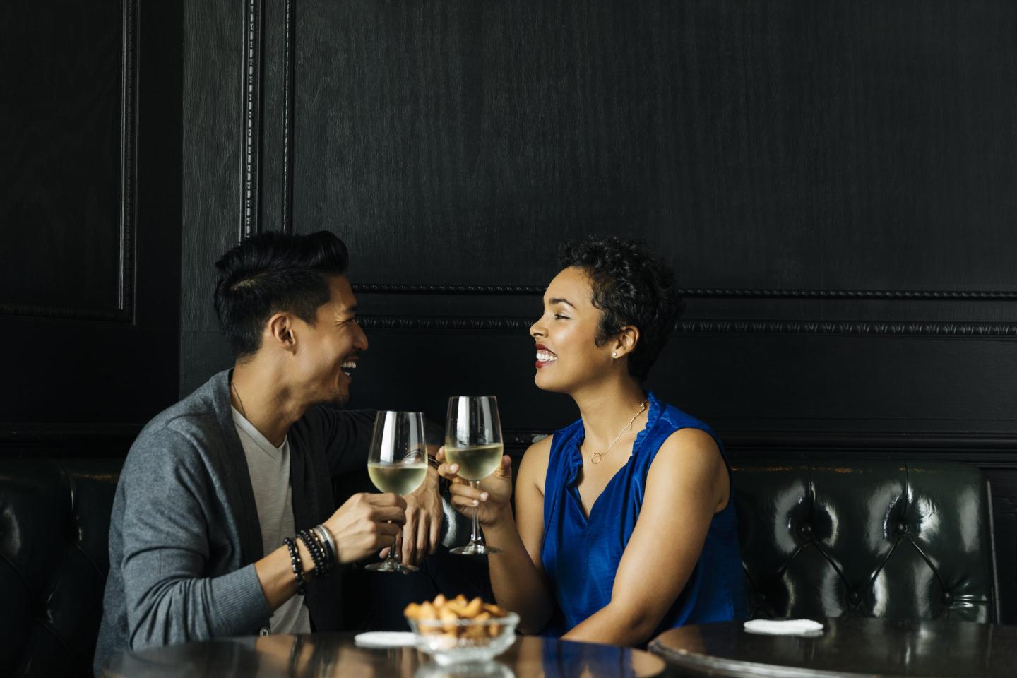 Two people sit at a table with glasses of wine in their hands
