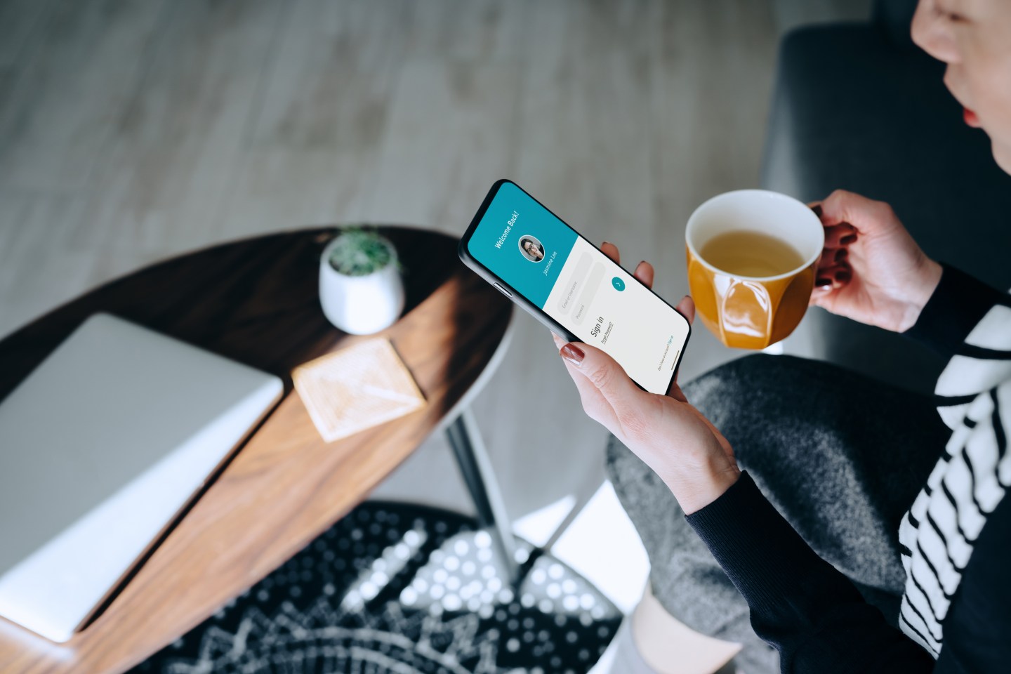 Young Asian woman relaxing at home drinking a cup of tea, logging in to her smartphone device. Lifestyle business, privacy protection, internet and mobile security concept
