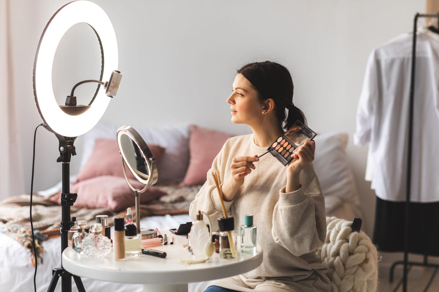 Make up artist demonstrating eye shadow palette while recording a video at home