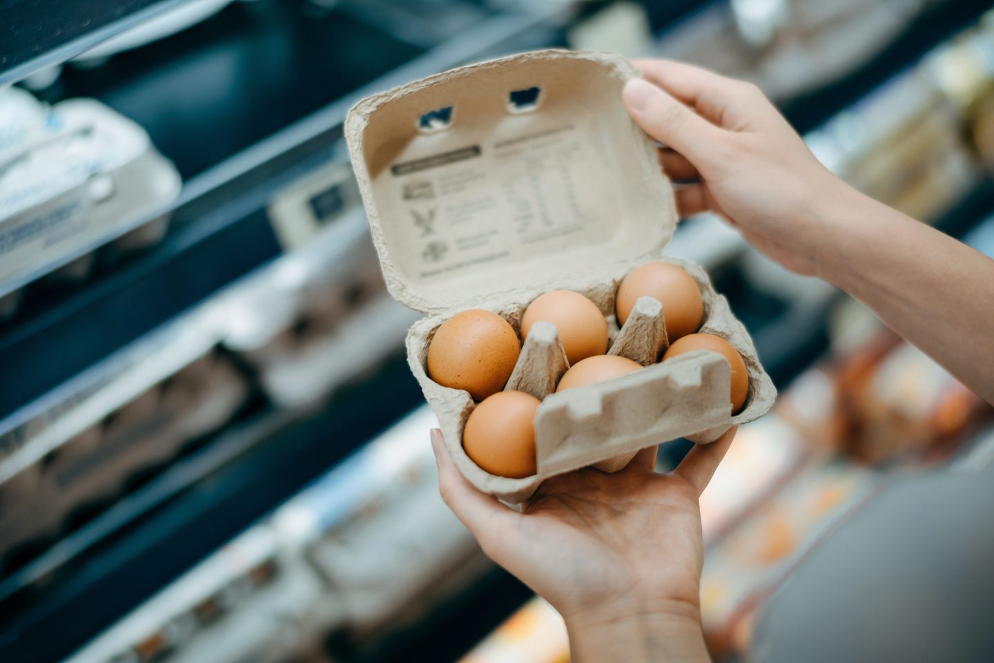 Close up of a woman's hands holding a box of six eggs