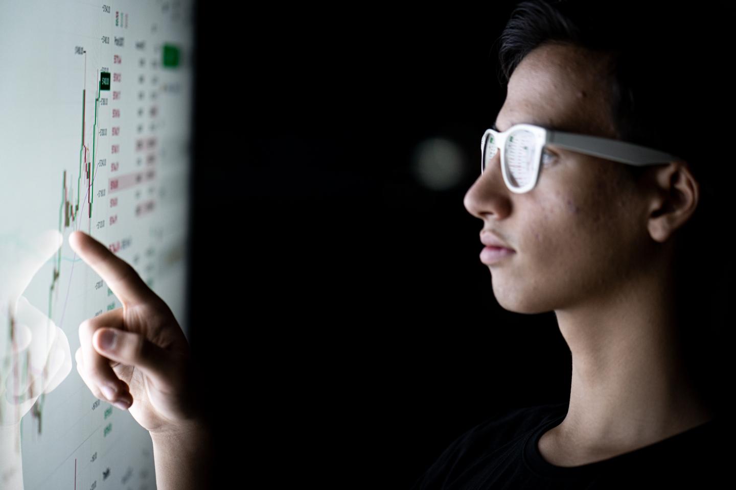 A boy with glasses staring at a smart screen