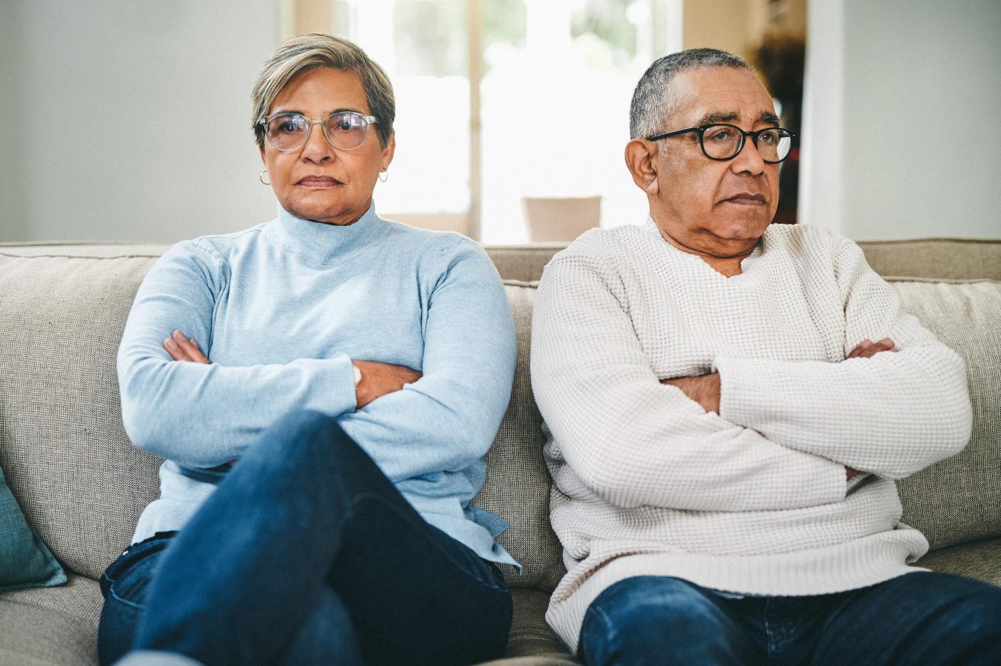 An unhappy couple sit on a sofa