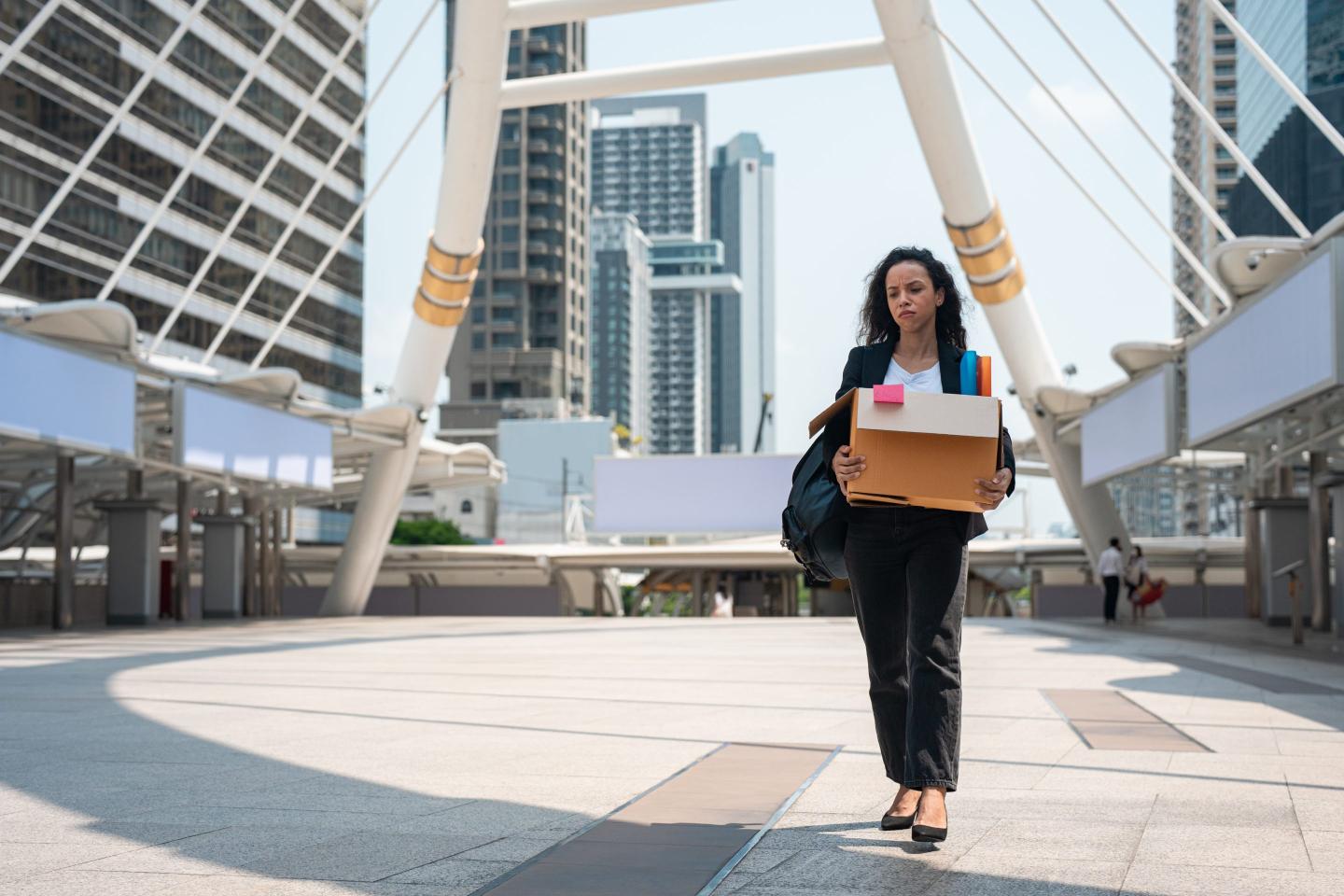 Laid-off worker carries a box of her belongings