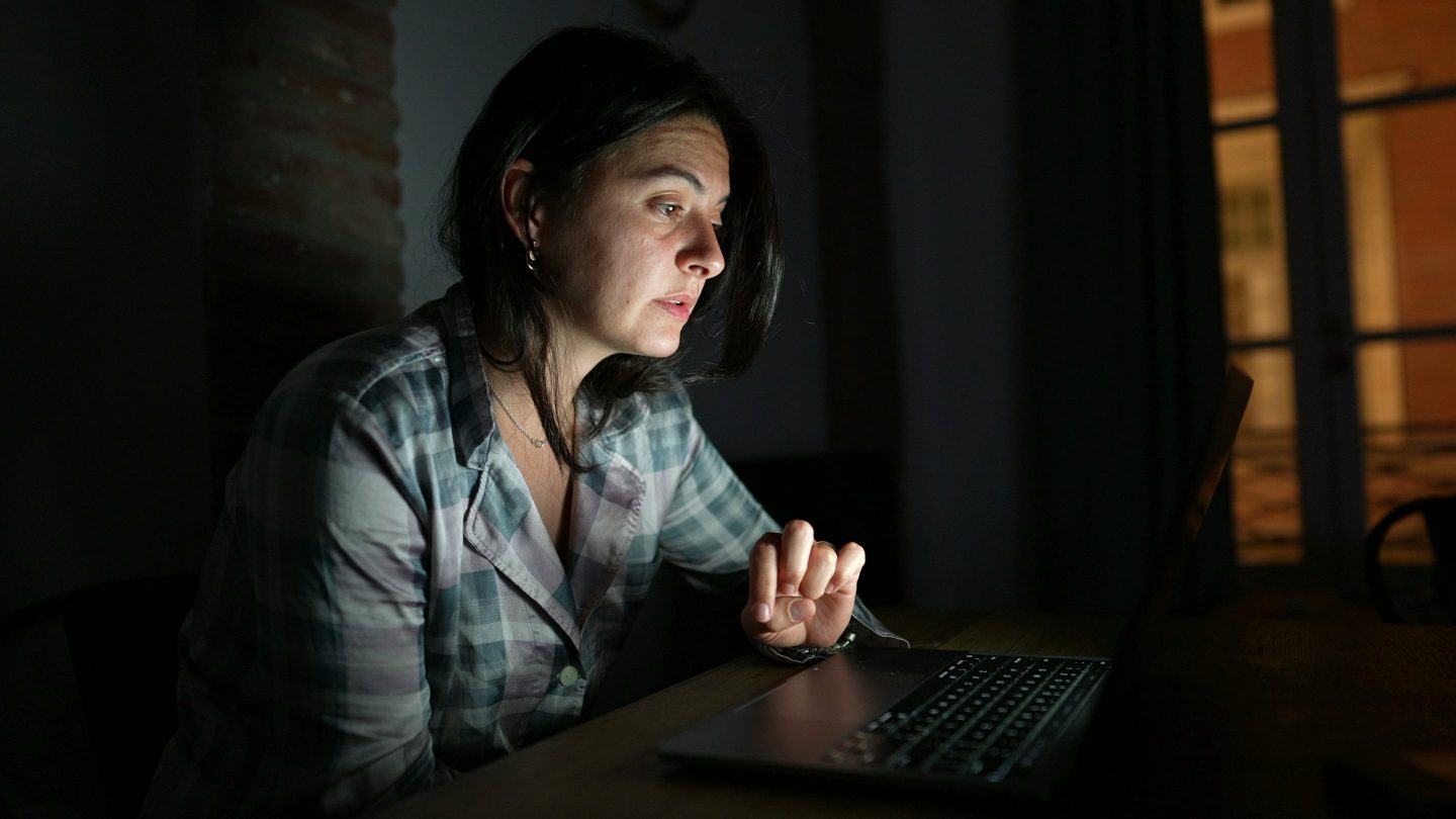 Pensive-looking woman working on a laptop