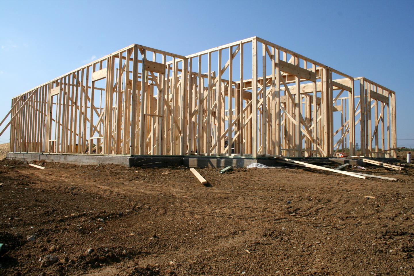 An unfinished home on a dirt construction lot.