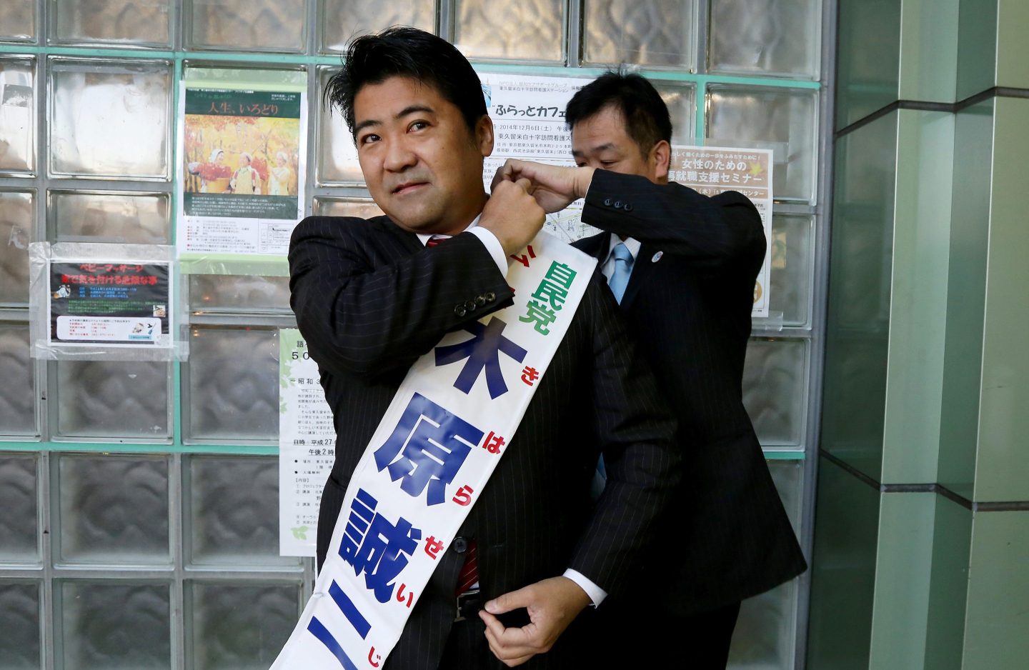 Seiji Kihara, a candidate for the Liberal Democratic Party, wears a sash bearing his name during his national election campaign at a train station in Tokyo, Japan, on Saturday, Dec. 6, 2014.