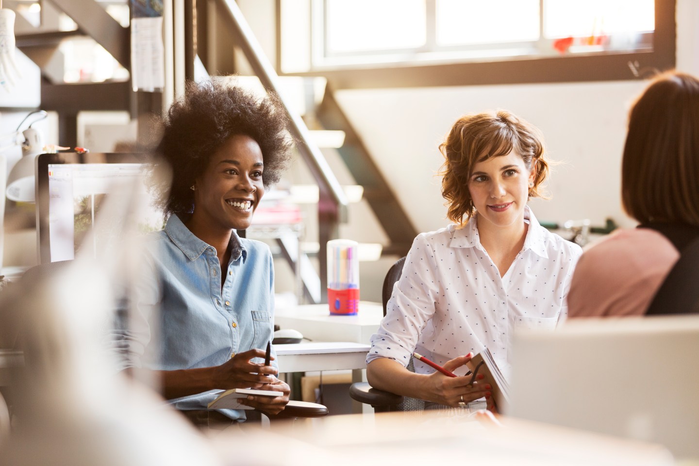 Three female workers are engaged in an office meeting,
