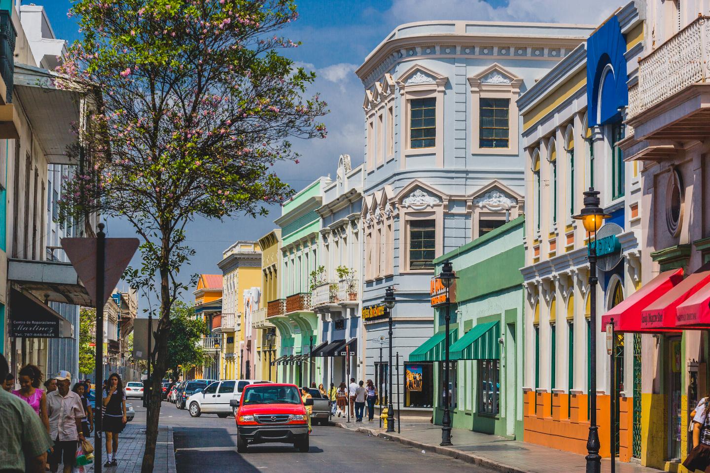 A car drives down a colorful street in Puerto Rico.