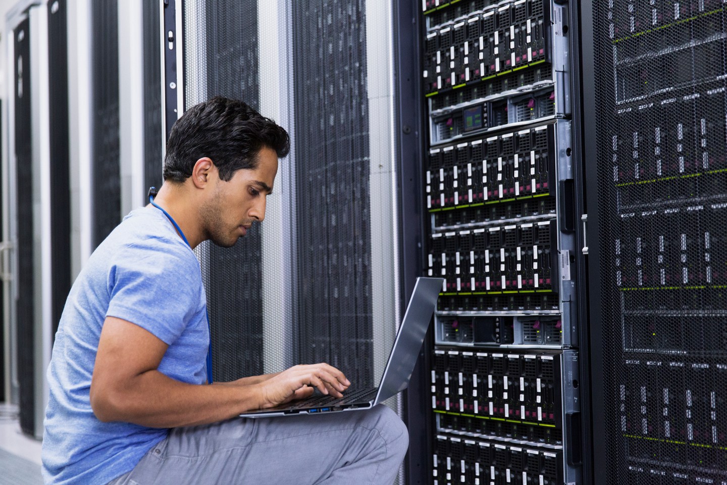 A man working on a laptop in a modern server room