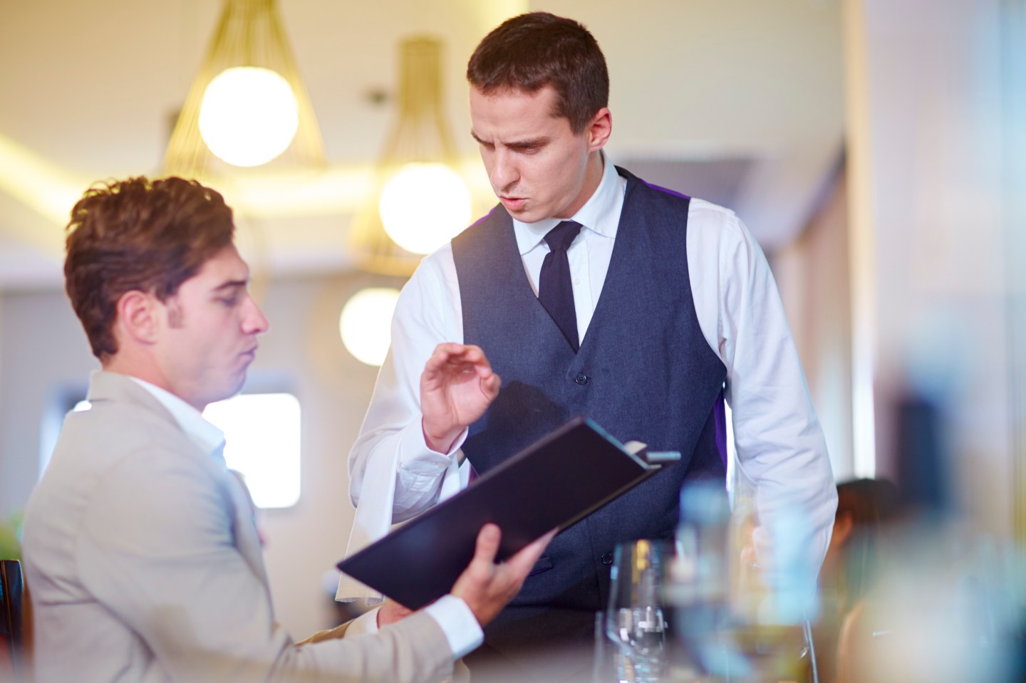 A man ordering from a waiter in a restaurant.