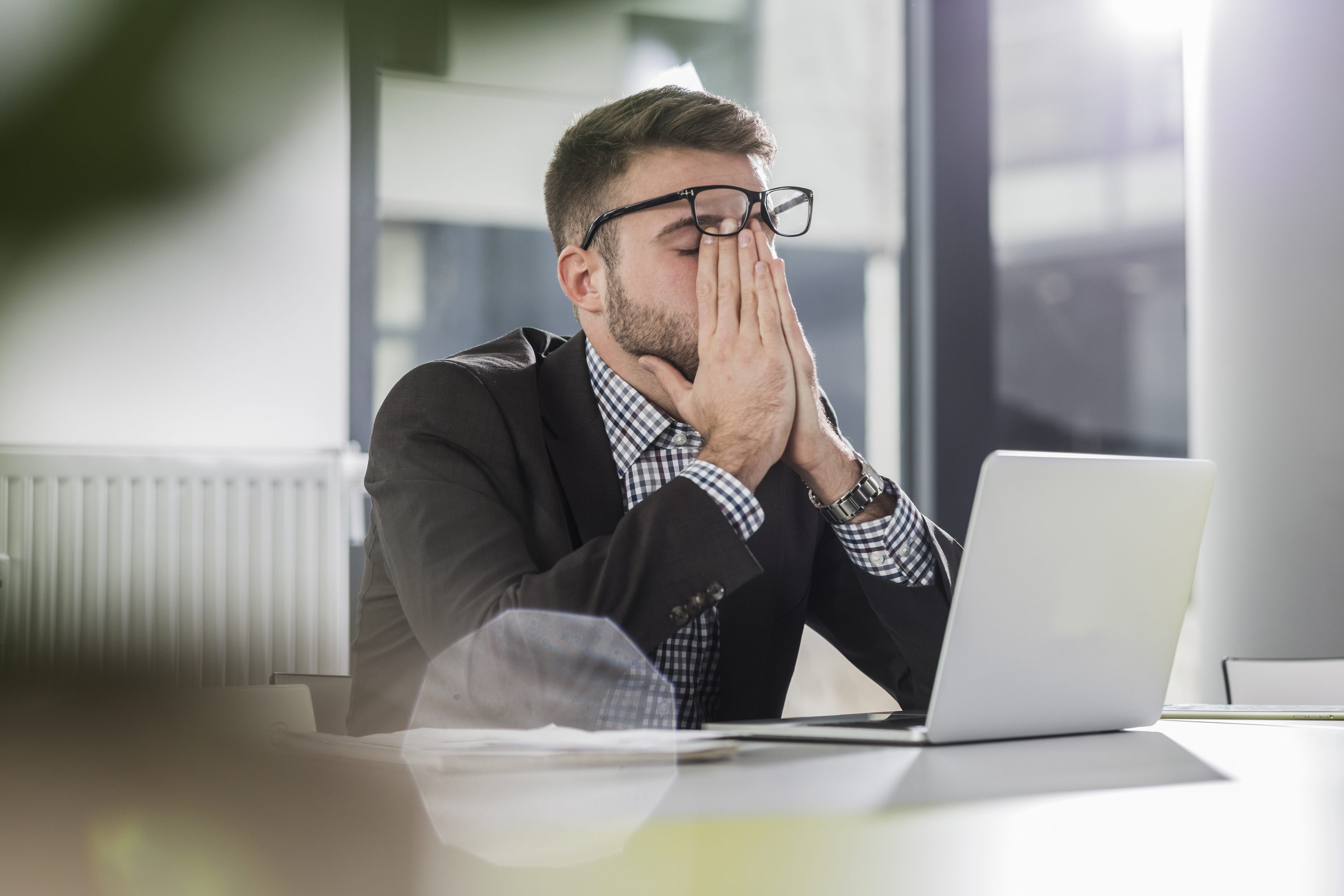A man sitting at his laptop looking burned out.