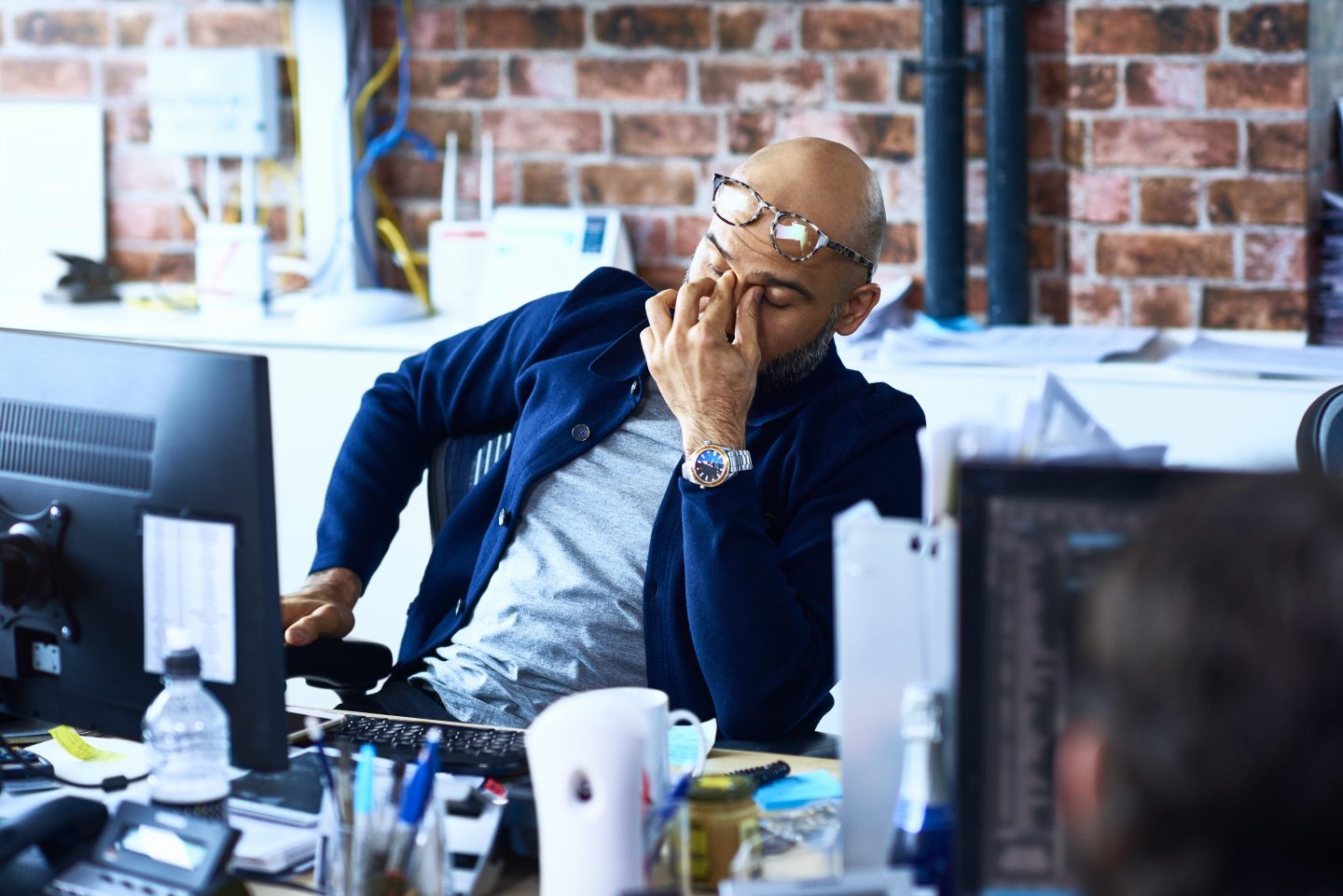 Photo of a tired man sitting at his desk in a modern office