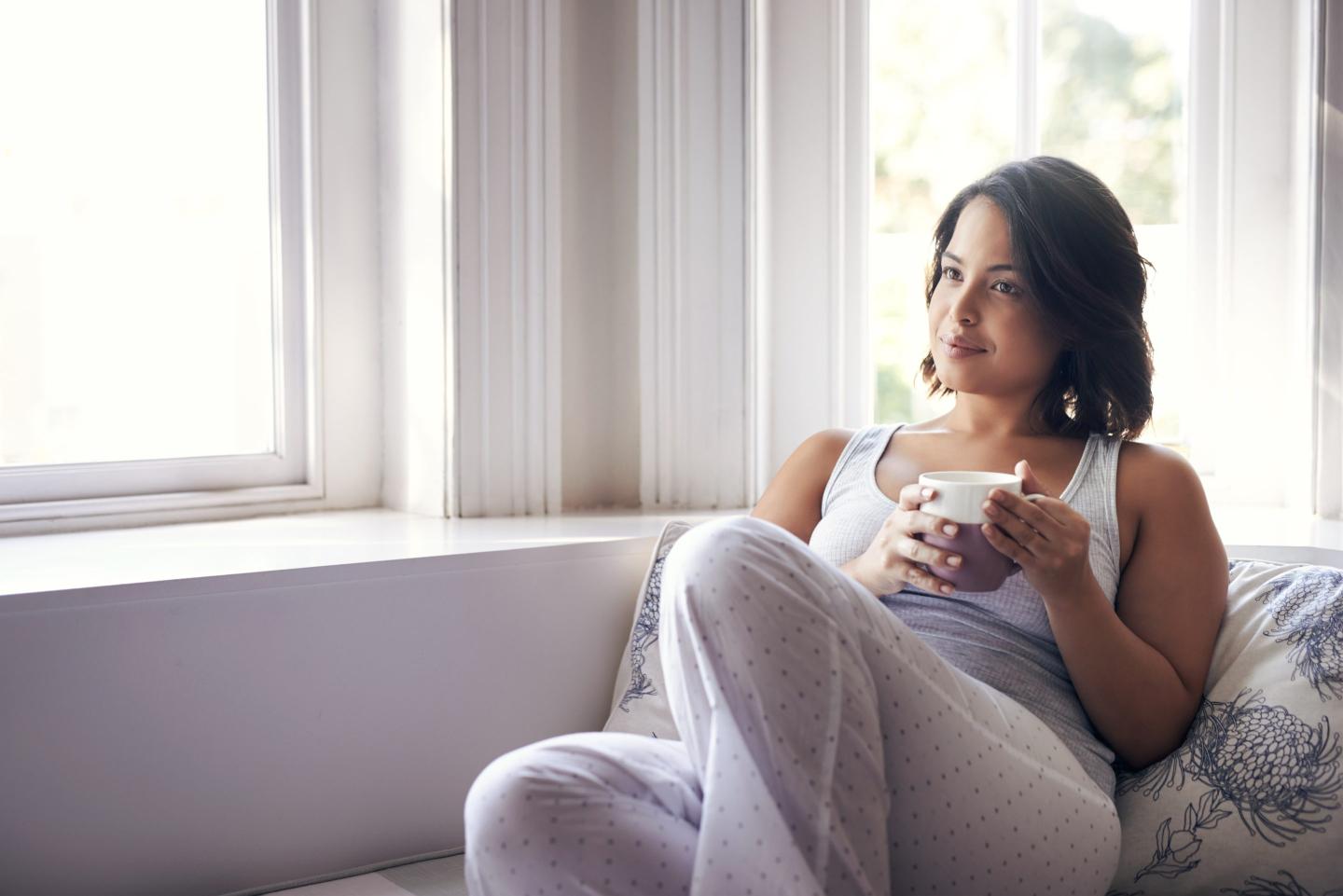 Shot of a young woman relaxing on the sofa with a cup of coffee