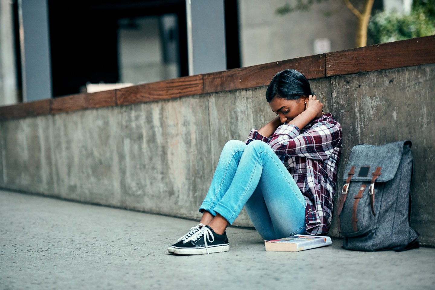 Female student looking defeated sitting down on the floor holding her head in her hands