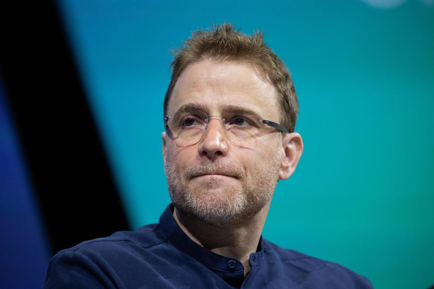 Slack CEO Stewart Butterfield wearing blue shirt and glasses being interviewed