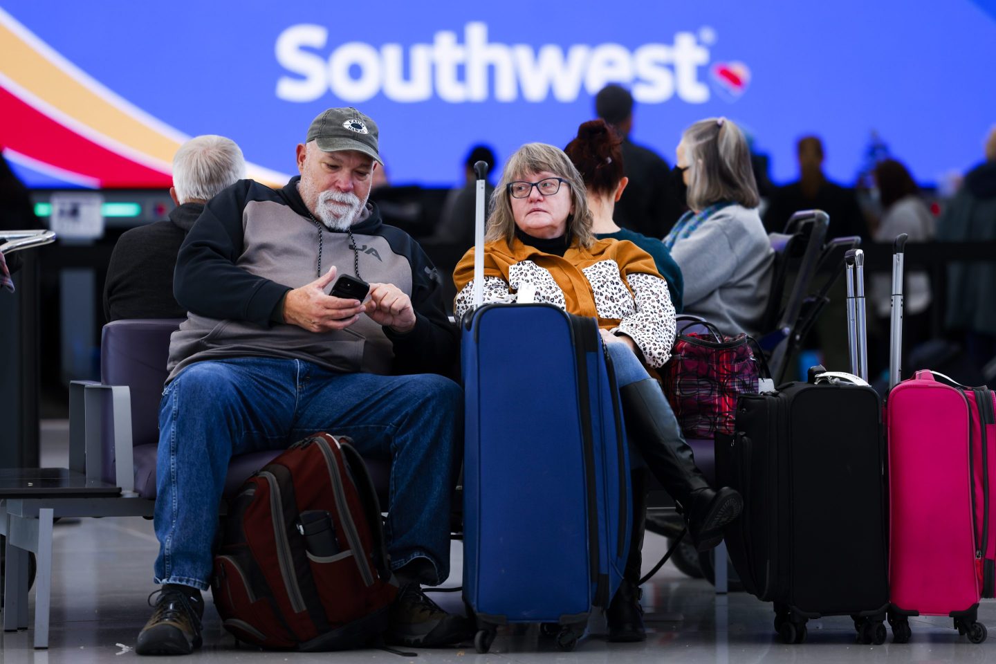 An unhappy couple sits with their luggage near a Southwest Airlines airport desk