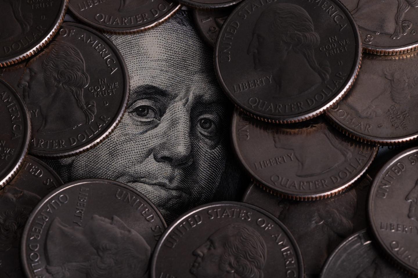 Benjamin Franklin's face from a $100 bill surrounded by quarters