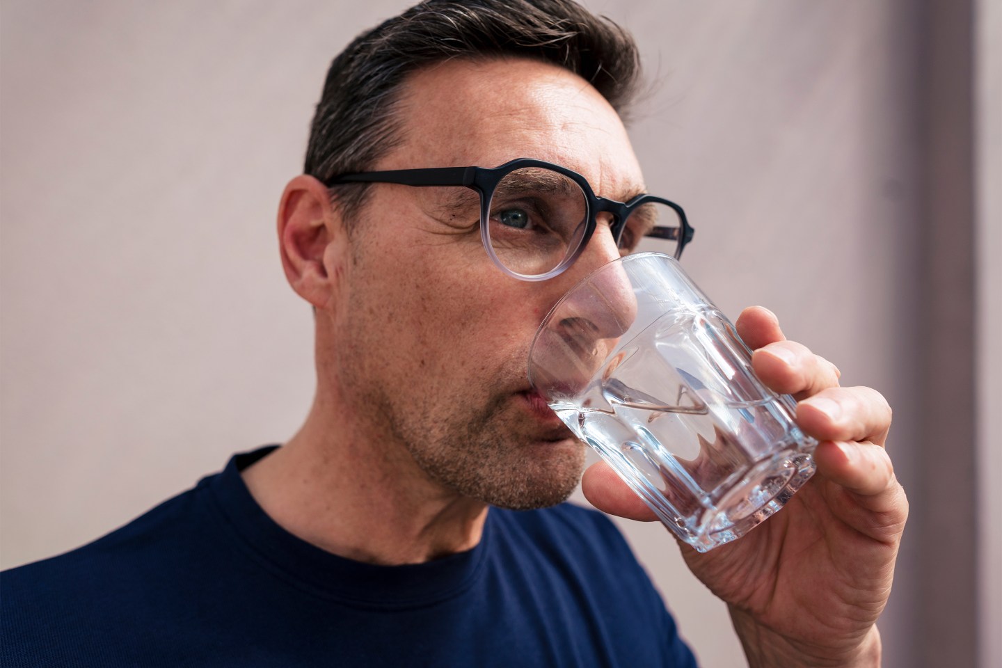 Businessman wearing eyeglasses drinking water in glass.