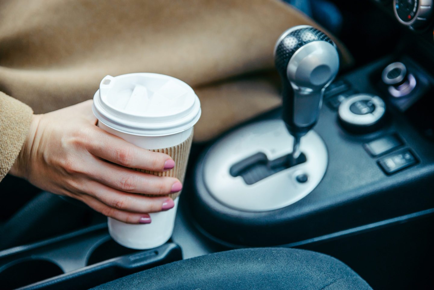 Woman grabbing coffee cup in car